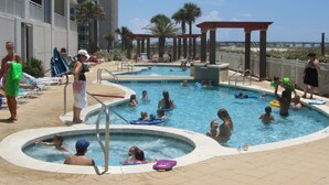 A pool area with multiple swimming pools, lounge chairs, and a covered seating area. - The Pearl #304 - FREE BEACH SETUP March-October! (Navarre Beach)