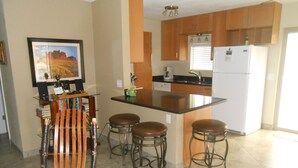 A kitchen with a bar stool area, a refrigerator, and a dining table with chairs. - Pool House - 3-bdrm, 2 bath, Heated Pool, Walk to Asu (Tempe)