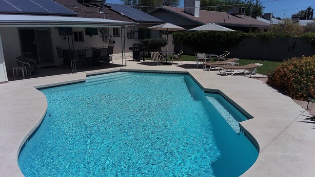 A swimming pool with a curved edge, surrounded by a concrete deck. - Pool House - 3-bdrm, 2 bath, Heated Pool, Walk to Asu (Tempe)