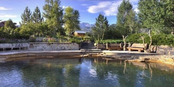 Relax by the serene pool surrounded by lush greenery and natural elements.
