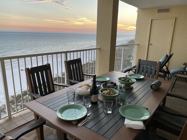 A table set for dining with a view of the ocean, a bottle of wine, and various dishes.