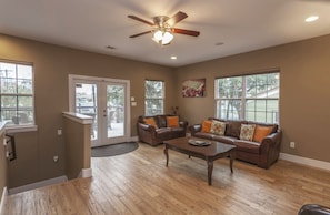 A spacious living room with a brown leather sofa set, a wooden coffee table, and a ceiling fan. - Stay for F1, ACL & UT — East Austin to downtown (Austin)