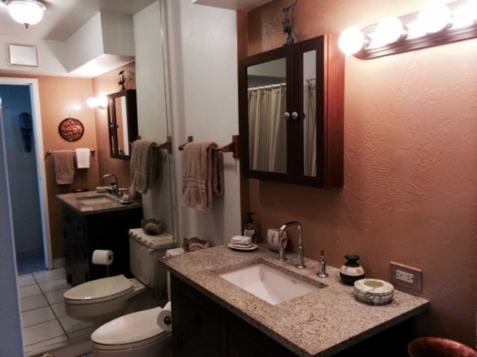 Un baño con lavamanos, espejo, toallero y retrete.