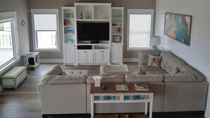 Een woonkamer met een grote flatscreen televisie, inbouwplanken, een bank en een salontafel.