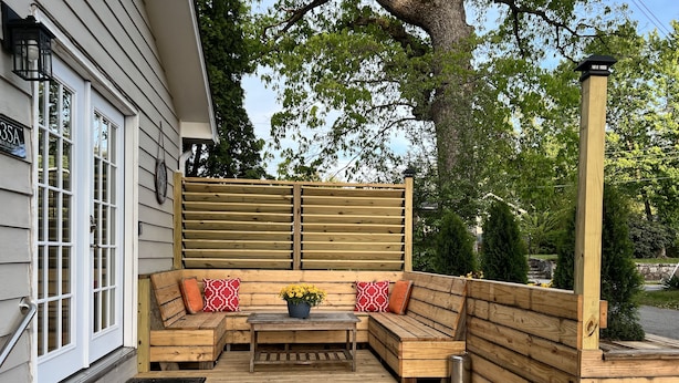 Una terraza de madera con un banco incorporado y una pequeña mesa, rodeada por una valla de madera.
