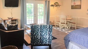 Una habitación con cama, una silla, una mesa y televisor.