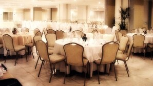 Un salón de banquetes con mesas y sillas redondas, dispuesto en un espacio amplio.