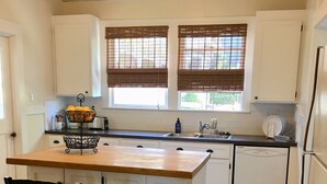 Een keuken met witte kasten, een houten kookeiland met twee stoelen, een spoelbak en een vaatwasser.