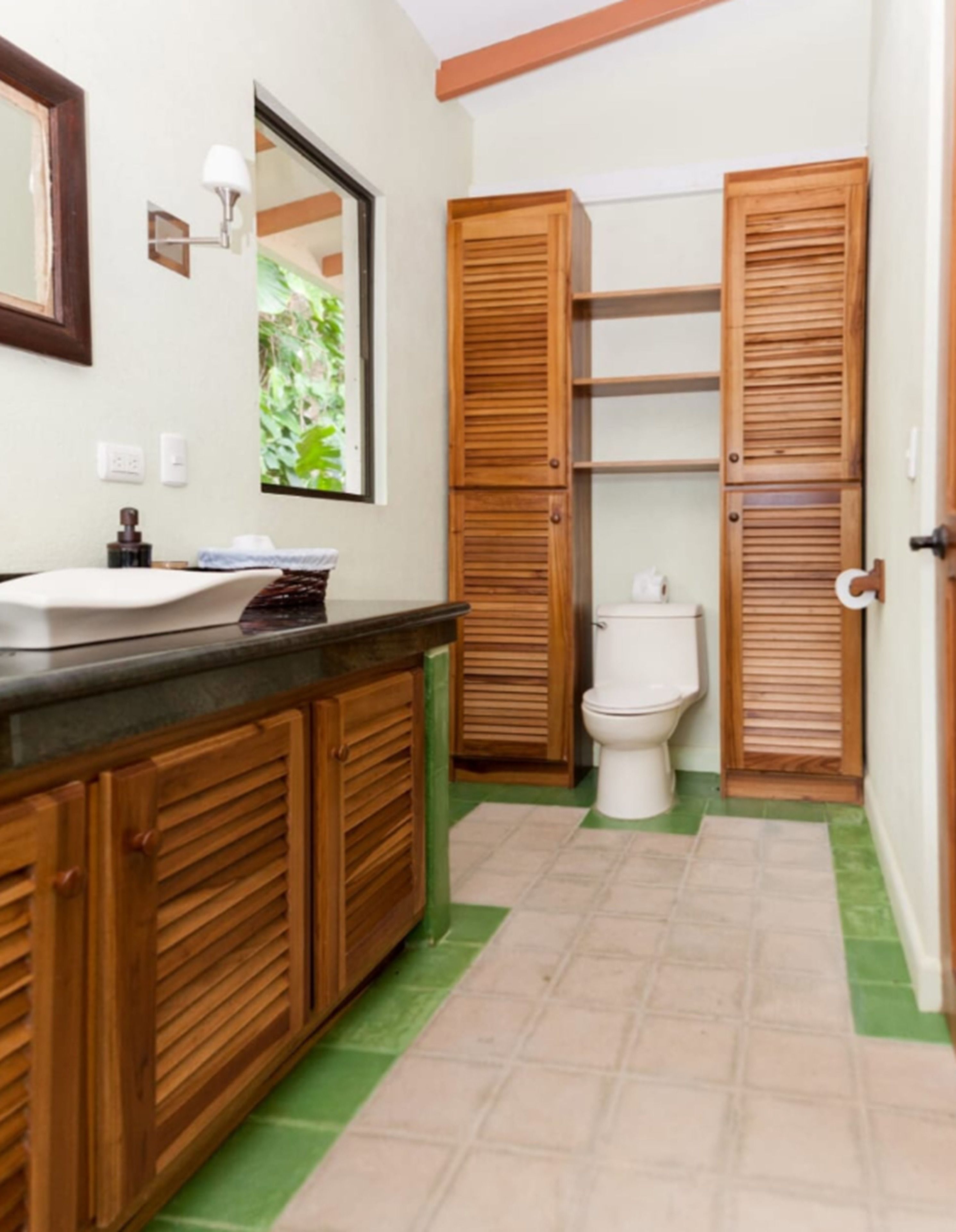 Un baño con armarios de madera, un lavabo, un inodoro y un espejo.