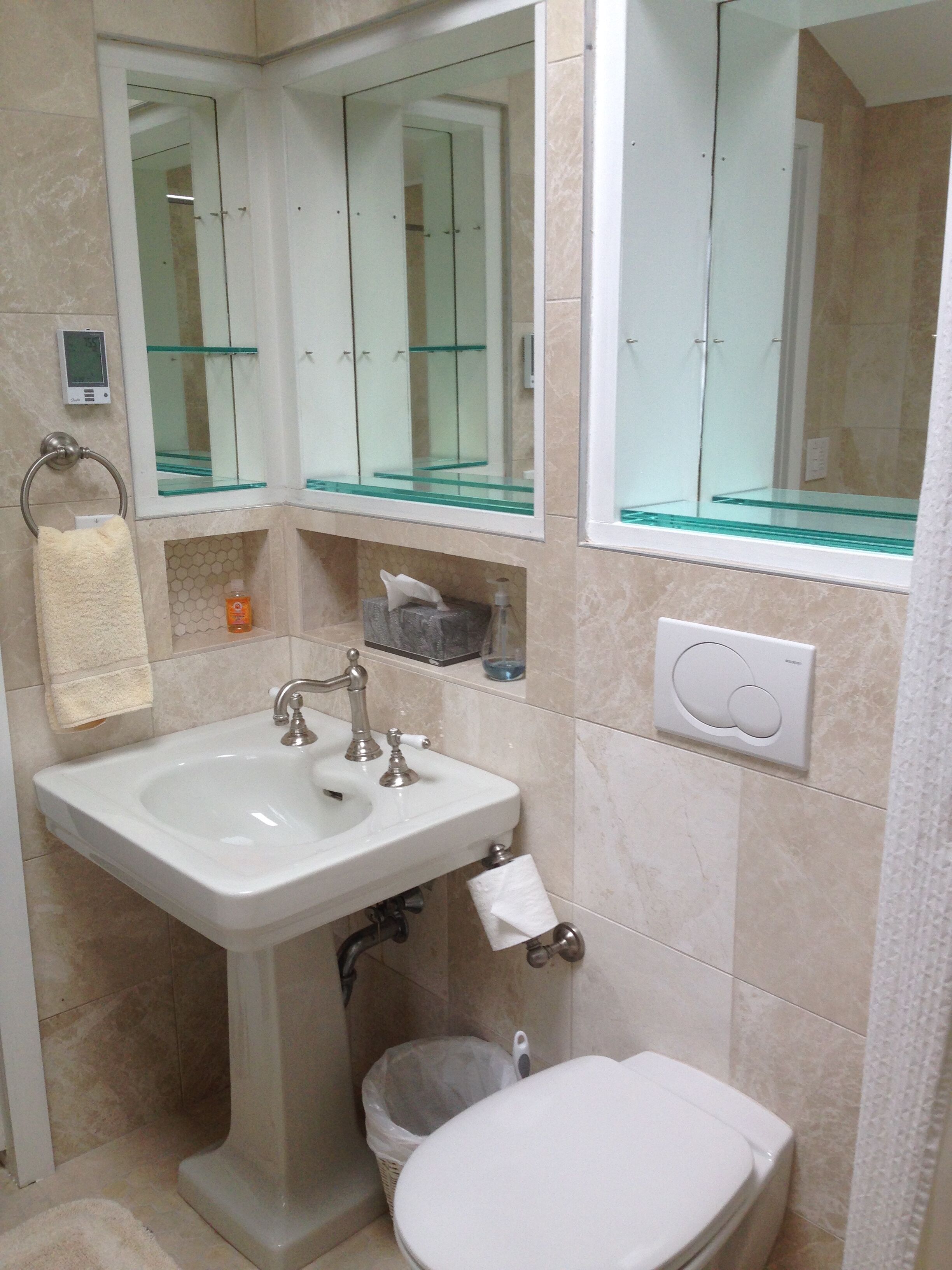 A bathroom with a white sink, a toilet, a glass shower enclosure, and a mirror above the sink.
