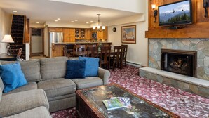 A spacious living room with a fireplace, a dining area, and a kitchen.
