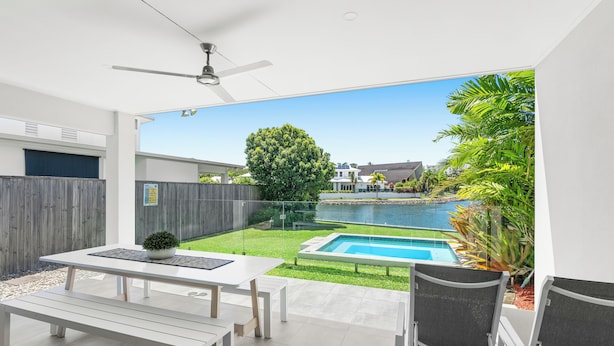 Un patio moderno con piscina, una mesa de comedor y sillas.