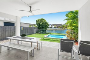 Une terrasse moderne avec une piscine, une table à manger et des chaises.