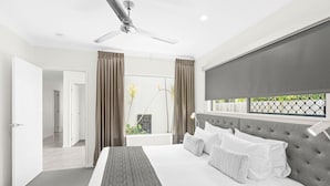 Una habitación de hotel moderna con una cama grande, un ventilador de techo y vistas al exterior.