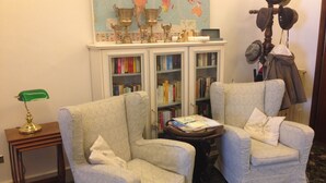 A room with two armchairs, a small table, a globe, and a bookshelf filled with books.
