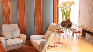 A room with a white sofa, a small table with a book, and a vase with flowers.