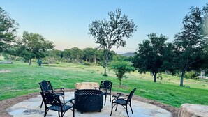 Eine Terrasse im Freien mit Steinboden, vier Stühlen und einem Feuerkorb.