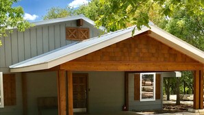 Ein rustikales Gebäude mit verdeckter Veranda, Steinmauerwerk und Holzbalken.