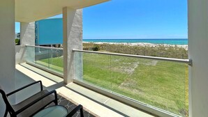 A balcony with a clear view of the beach and ocean.
