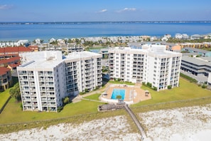A high-rise hotel with multiple balconies, a swimming pool, and a view of the ocean.