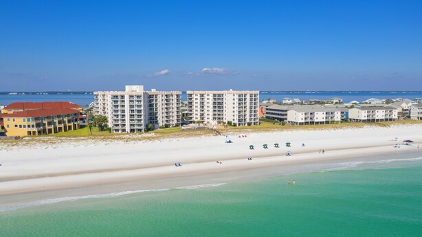 A beachfront hotel with multiple buildings, a sandy beach, and clear turquoise waters.