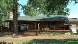 Une cabane rustique avec des fondations en pierre, un revêtement extérieur en bois et une véranda avec des marches menant à l’entrée.