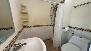 Un baño con lavamanos, inodoro, ducha y perchero para toallas.