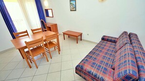Un salon avec un canapé, une table à manger avec des chaises et une petite table d’appoint.