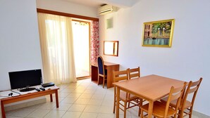 Une pièce comprenant une table à manger en bois, des chaises, un téléviseur et un bureau.