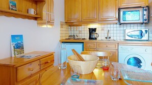 A compact kitchen with wooden cabinets, a microwave, a coffee maker, and a washing machine. - Beautiful apartment for 3 guests with WIFI, TV, balcony and pets allowed (Saint-gervais-les-bains)