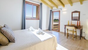 Een slaapkamer met een bed, een bureau en een stoel. Er is een raam en een deur die leidt naar een balkon.