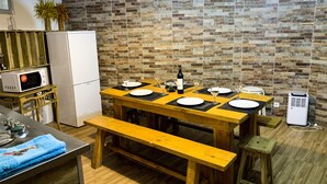 Eine kompakte Küche mit einem Holztisch, gedeckt für vier Personen, einer Mikrowelle, einem Kühlschrank und einem kleinen Luftreiniger.