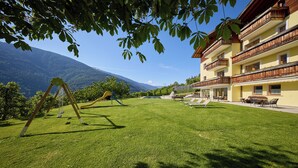 Un hotel con parque infantil, mobiliario exterior y vistas a la montaña.