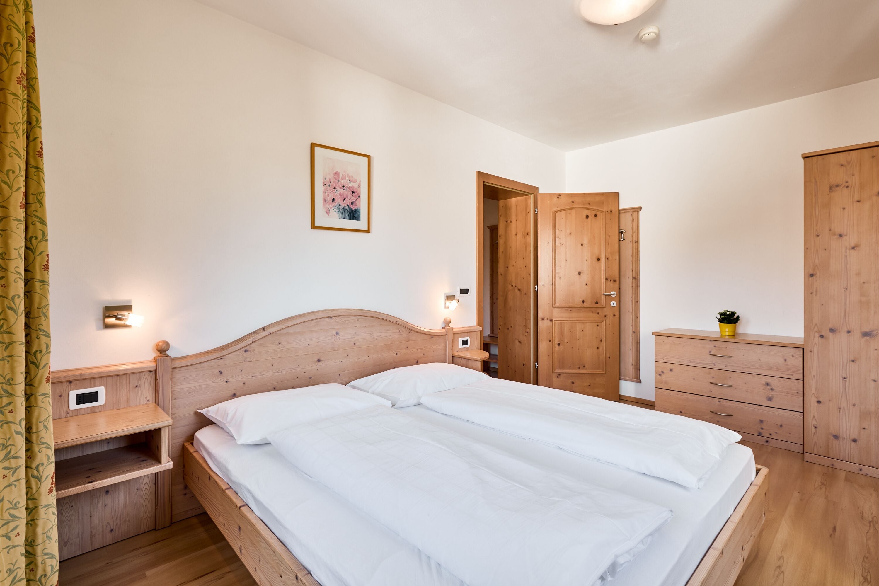 Una camera da letto con un letto in legno, comodini, una cassettiera e un armadio.