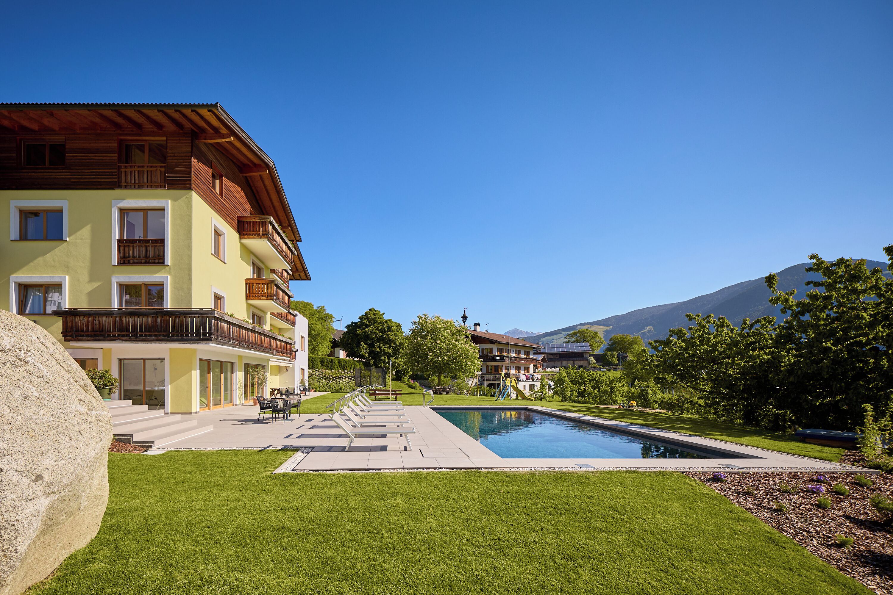 Un hôtel doté d’une piscine, d’un espace extérieur aménagé et offrant une vue sur les montagnes.