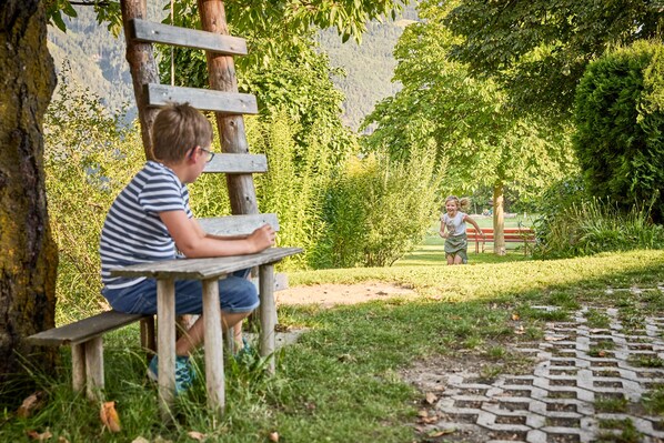 Un banco de madera en un parque con un sendero pavimentado y vegetación.