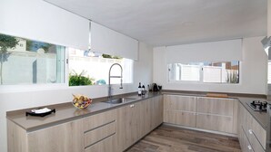 Eine moderne Küche mit einem großen Fenster, Holzschränken und einem Fischgrätparkettboden.