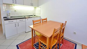 Eine kleine Küche mit weißen Schränken, einem Holzespeisetisch und einem Teppich in Rot und Blau.