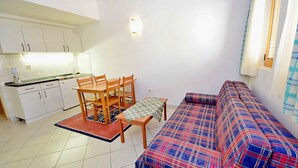 Ein kompakter Wohnbereich mit Küchenzeile, einem Esstisch mit Stühlen und einer Couch.