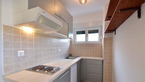 A compact kitchen with a gas stove, a built-in oven, a dishwasher, and a window above the sink. - Beautiful  villa for 12 people with WIFI, TV and terrace (Crikvenica)