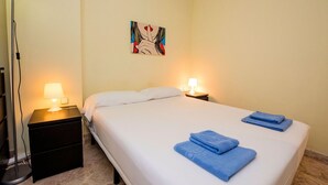 A hotel room with a bed, two bedside lamps, a floor lamp, and a painting on the wall. - Nice apartment for 3 people with WIFI, A/C and TV (Barcelona)