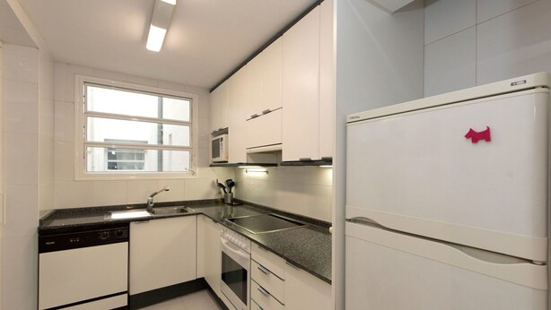 A modern kitchen with white cabinets, a built-in oven, a microwave, and a refrigerator. - Nice apartment for 3 people with WIFI, A/C and TV (Barcelona)
