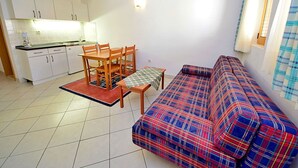 A compact living space with a kitchenette, a dining table with chairs, and a sofa.