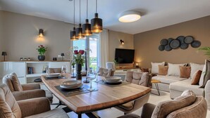 A modern living room with a wooden dining table, comfortable sofas, and a flat-screen TV mounted on the wall. - Beautiful  villa for 6 guests with WIFI, A/C, private pool, TV, terrace and panoramic view (Pazin)