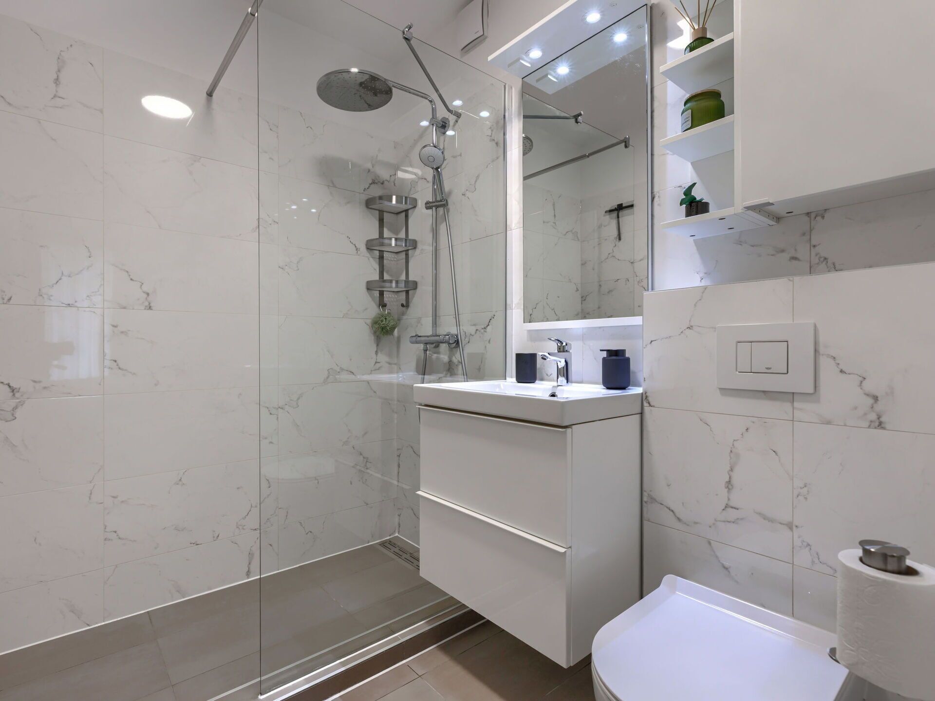 A modern bathroom with a glass-enclosed shower, a white vanity with a mirror, and a toilet.