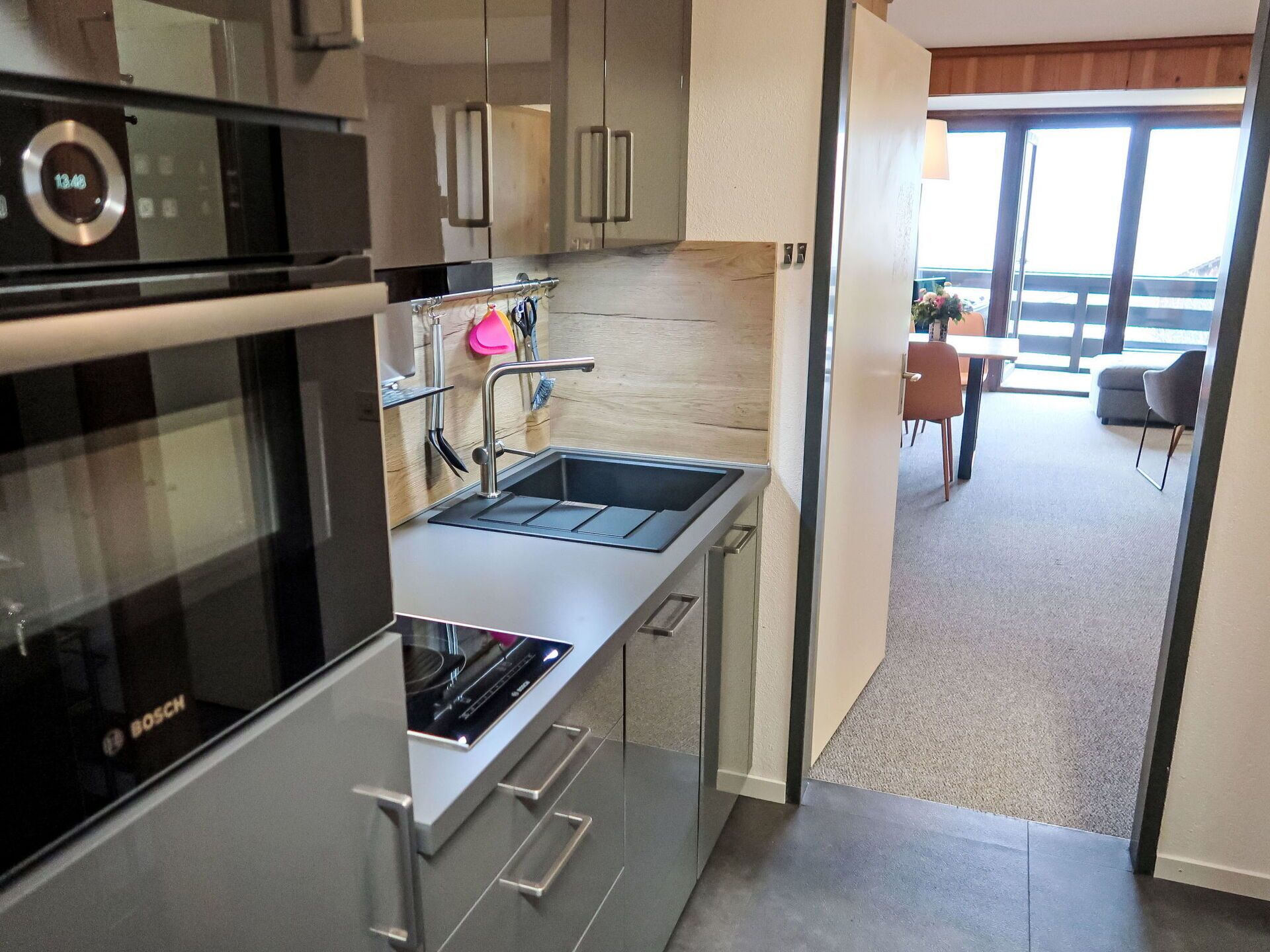 A modern kitchen with a Bosch oven, stainless steel appliances, and a sink.
