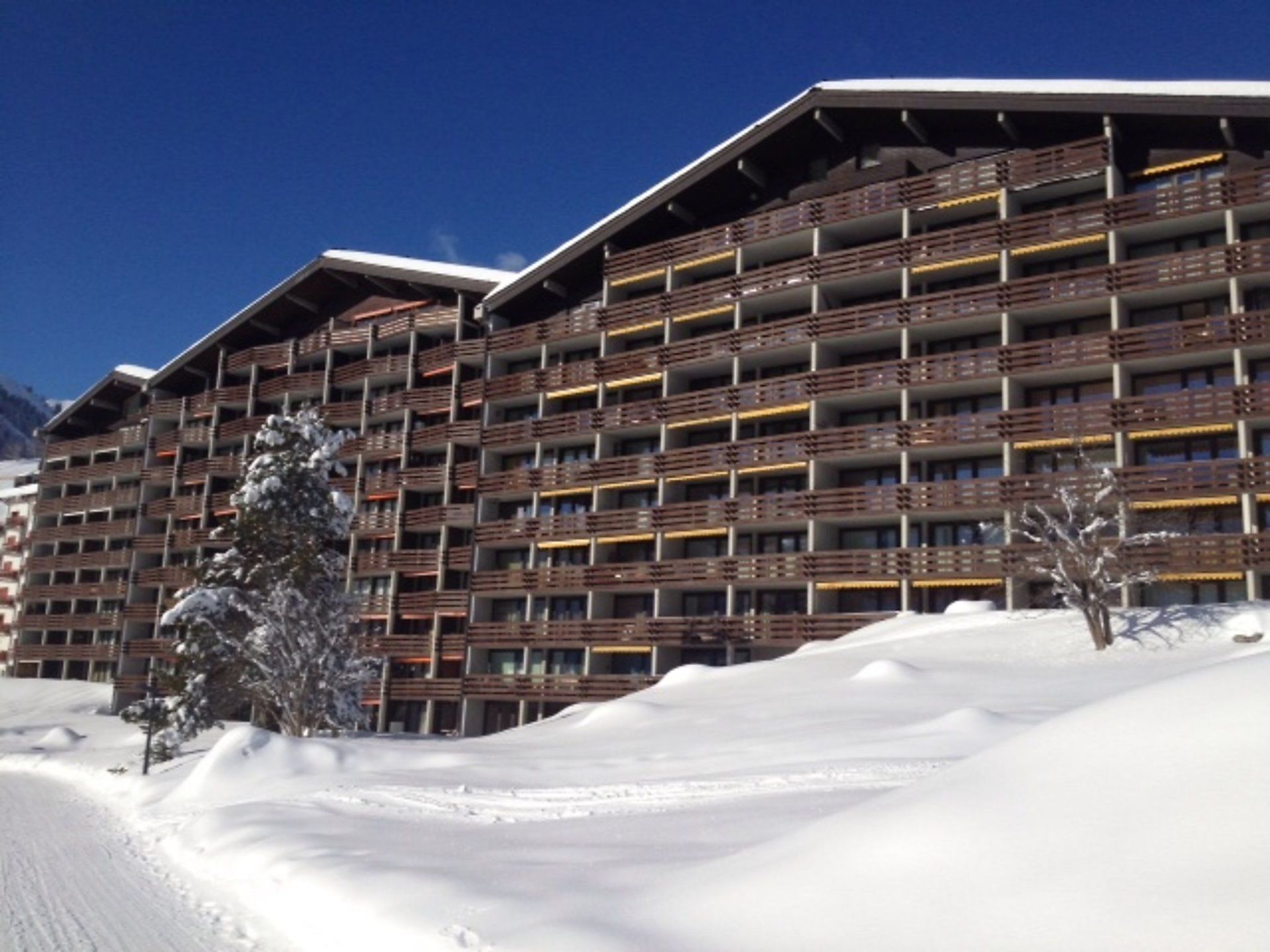 A multi-story hotel with balconies and a snowy landscape.