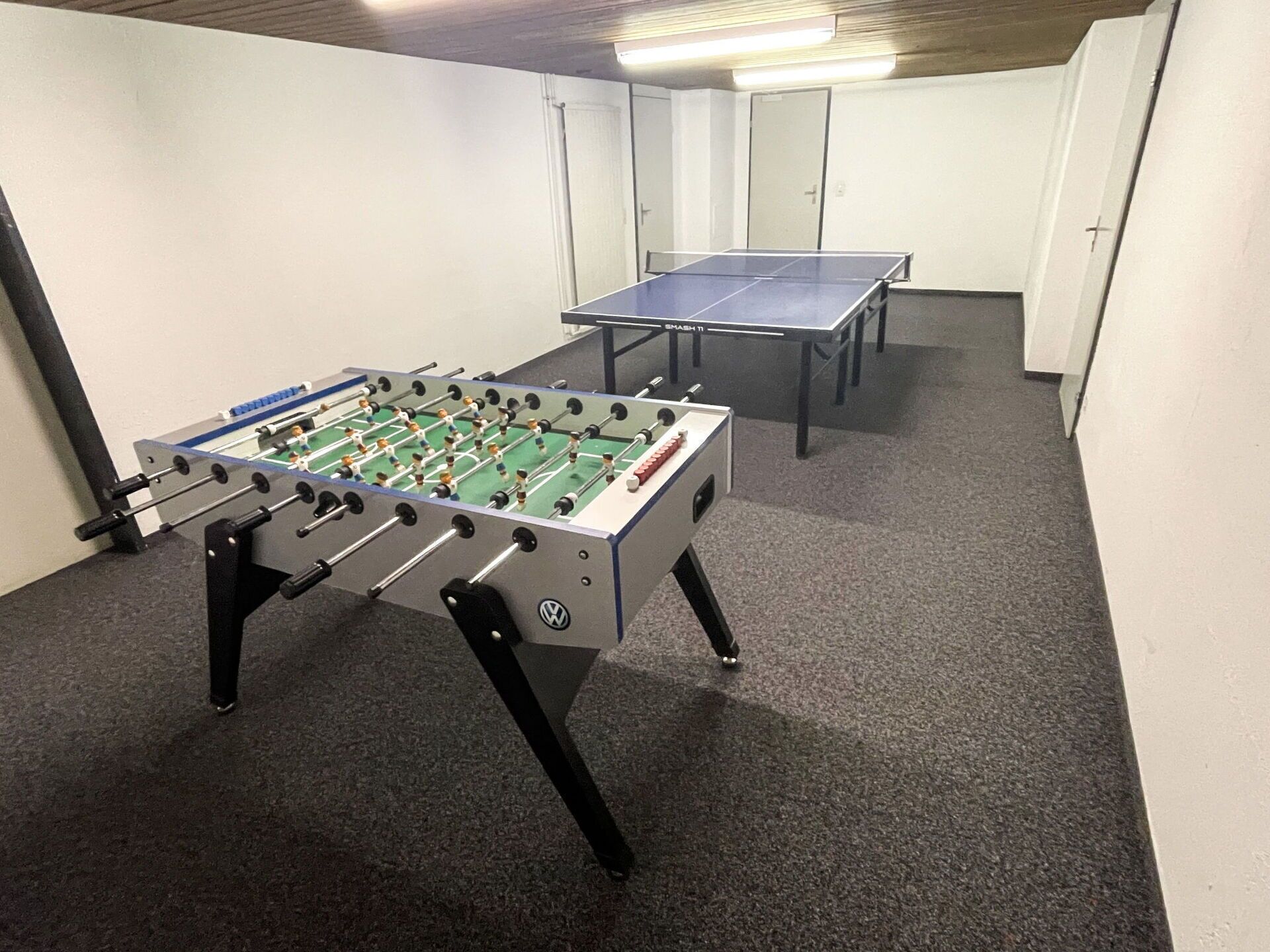 Una habitació amb dues taules de futbolí i una taula de bitlles.