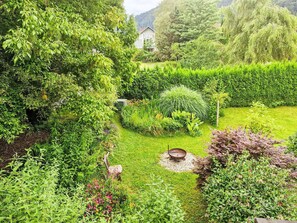 A lush garden with a variety of plants and a small fire pit.