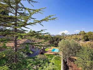 A residential area with a swimming pool, a stone building, and surrounding greenery.